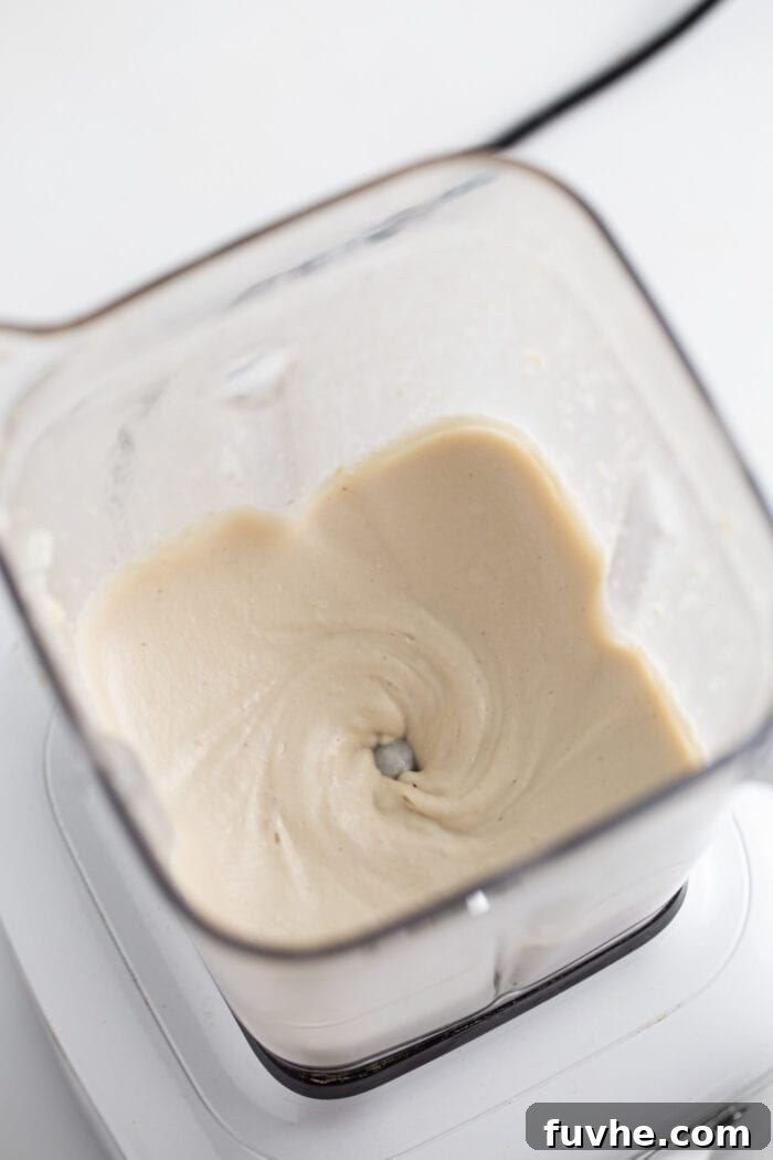 A high-speed blender filled with creamy, smooth cashew frosting, ready to be spread.