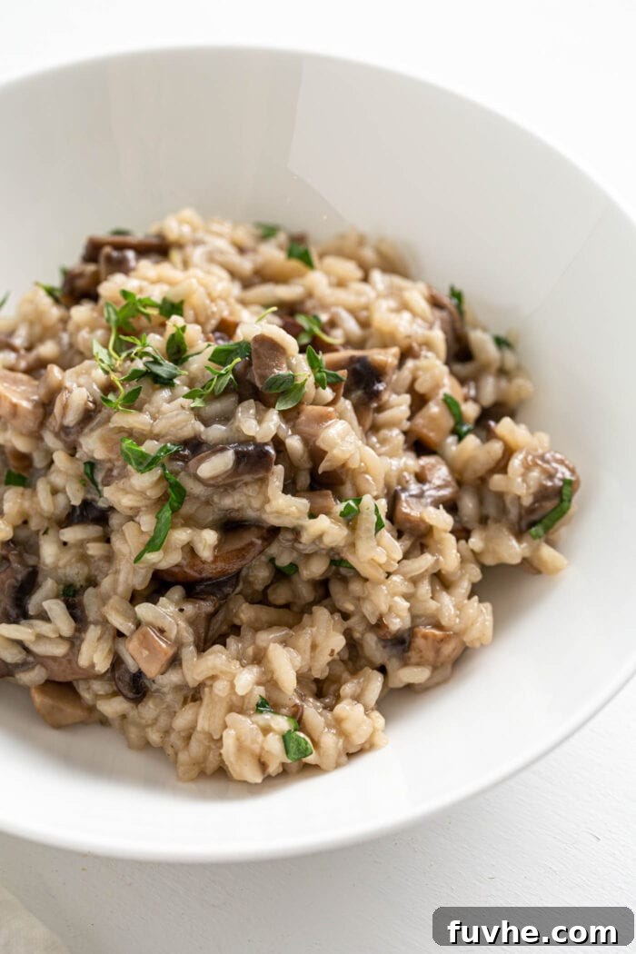 A close-up shot of a bowl of rich and creamy vegan mushroom risotto, beautifully garnished with fresh green parsley, highlighting its appetizing texture.