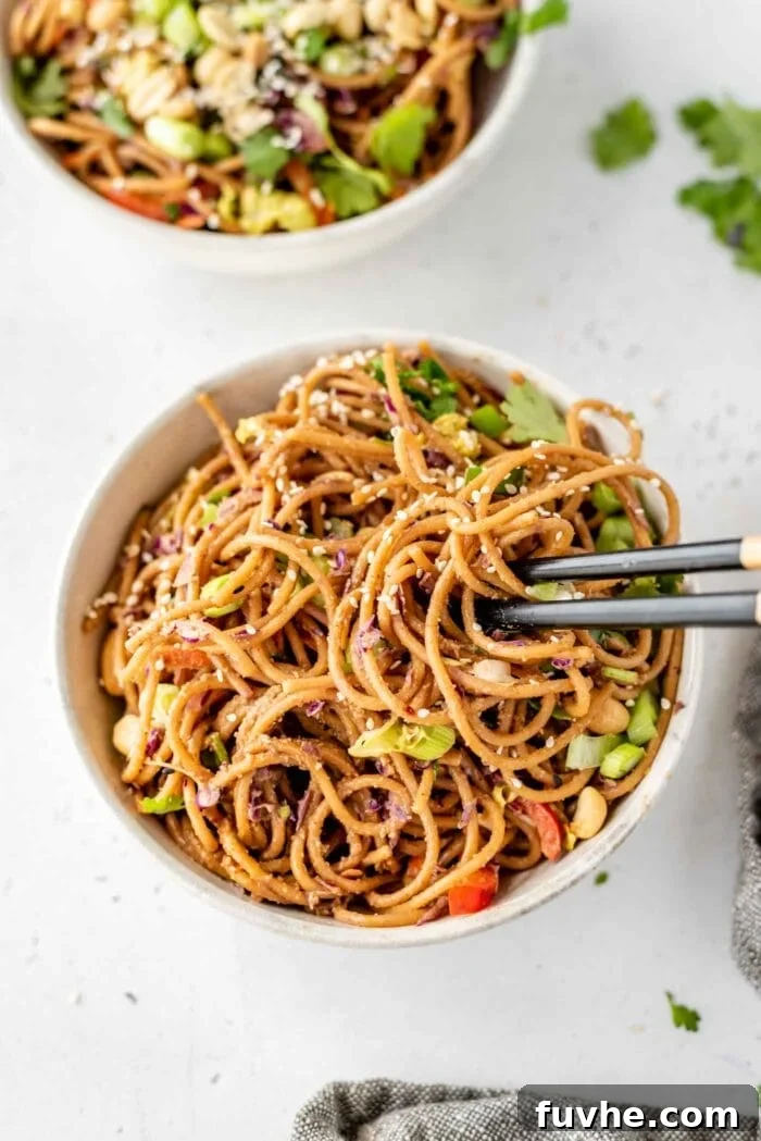 Refreshing Asian Peanut Noodles 8 Chopsticks in a bowl of noodles mixed with vegetables.