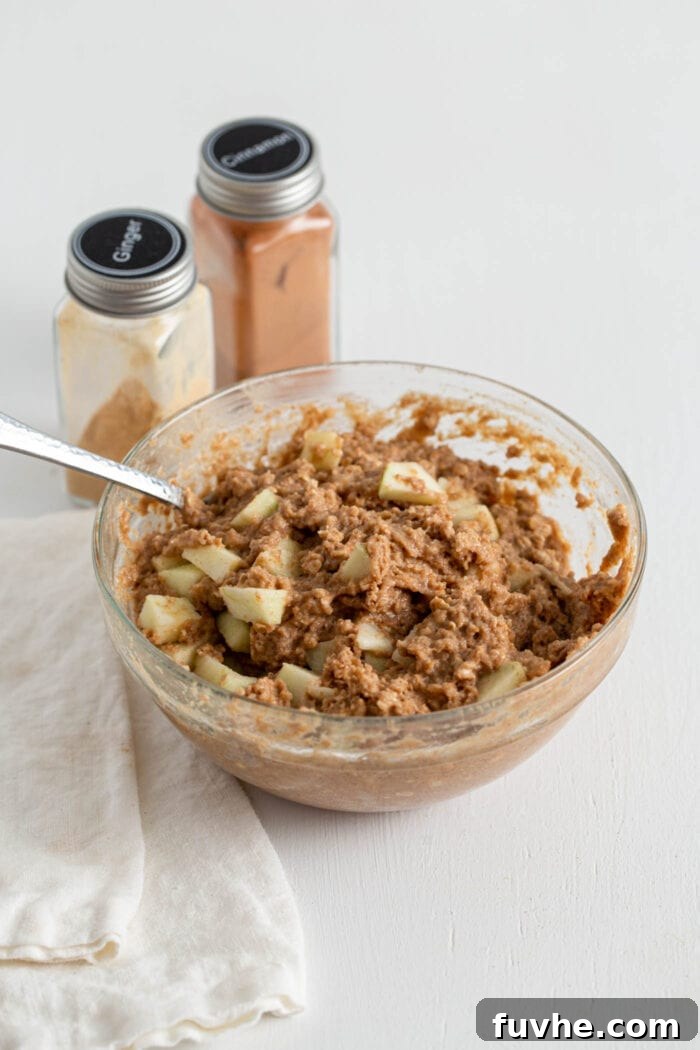 Muffin batter with diced apple mixed into it in a mixing bowl.