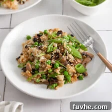 Mushroom fried rice topped with scallions and sesame seeds in a bowl.