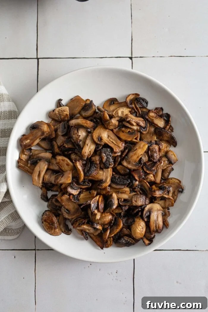 A plate filled with an assortment of perfectly cooked and browned mushrooms, ready to be added back into the fried rice.