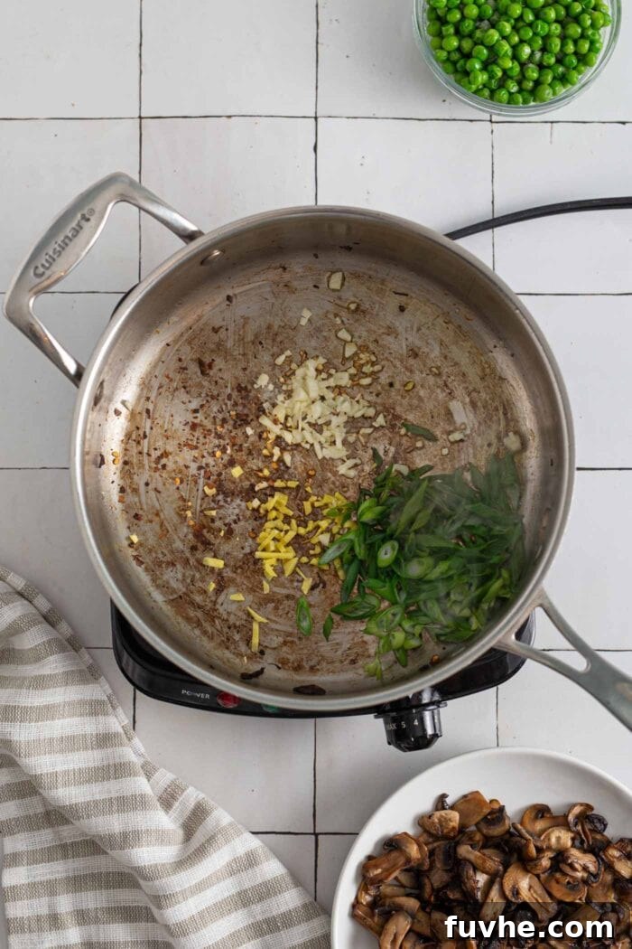 Finely grated ginger and minced garlic sizzling in a large skillet, creating a fragrant base for the fried rice.
