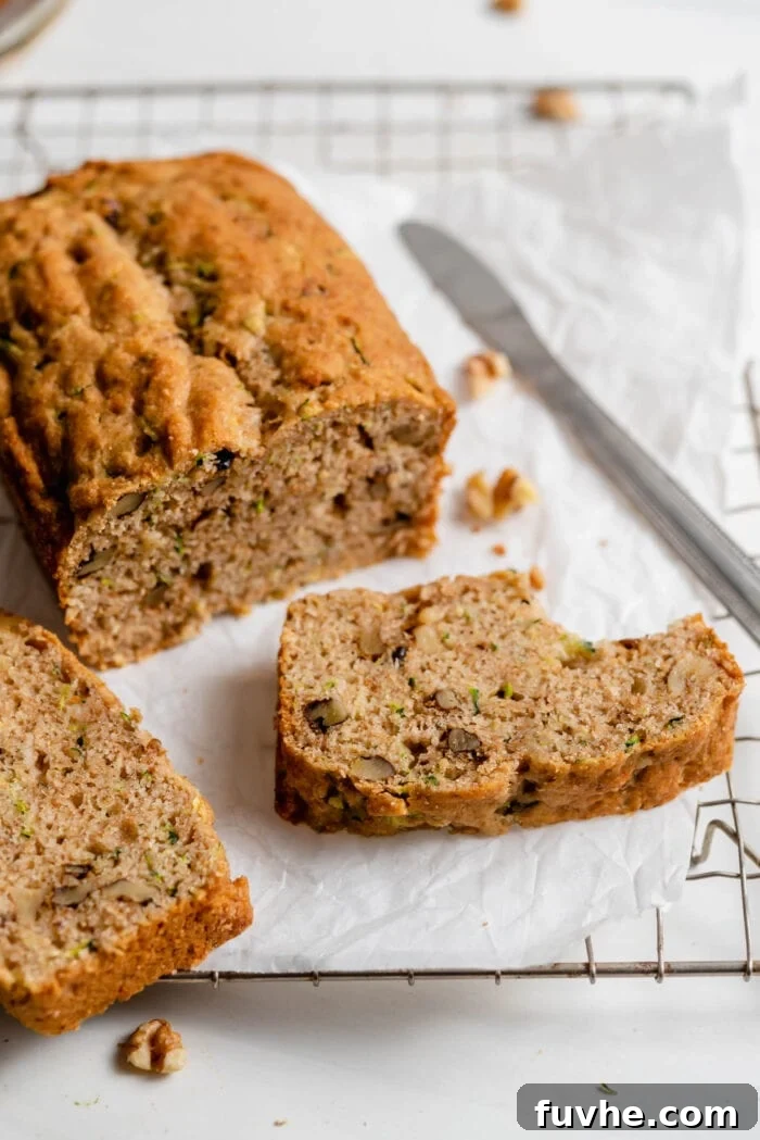 Wholesome Plant-Based Zucchini Bread 13 Sliced zucchini loaf resting on parchment paper on top of a cooling rack, showing off its moist interior.