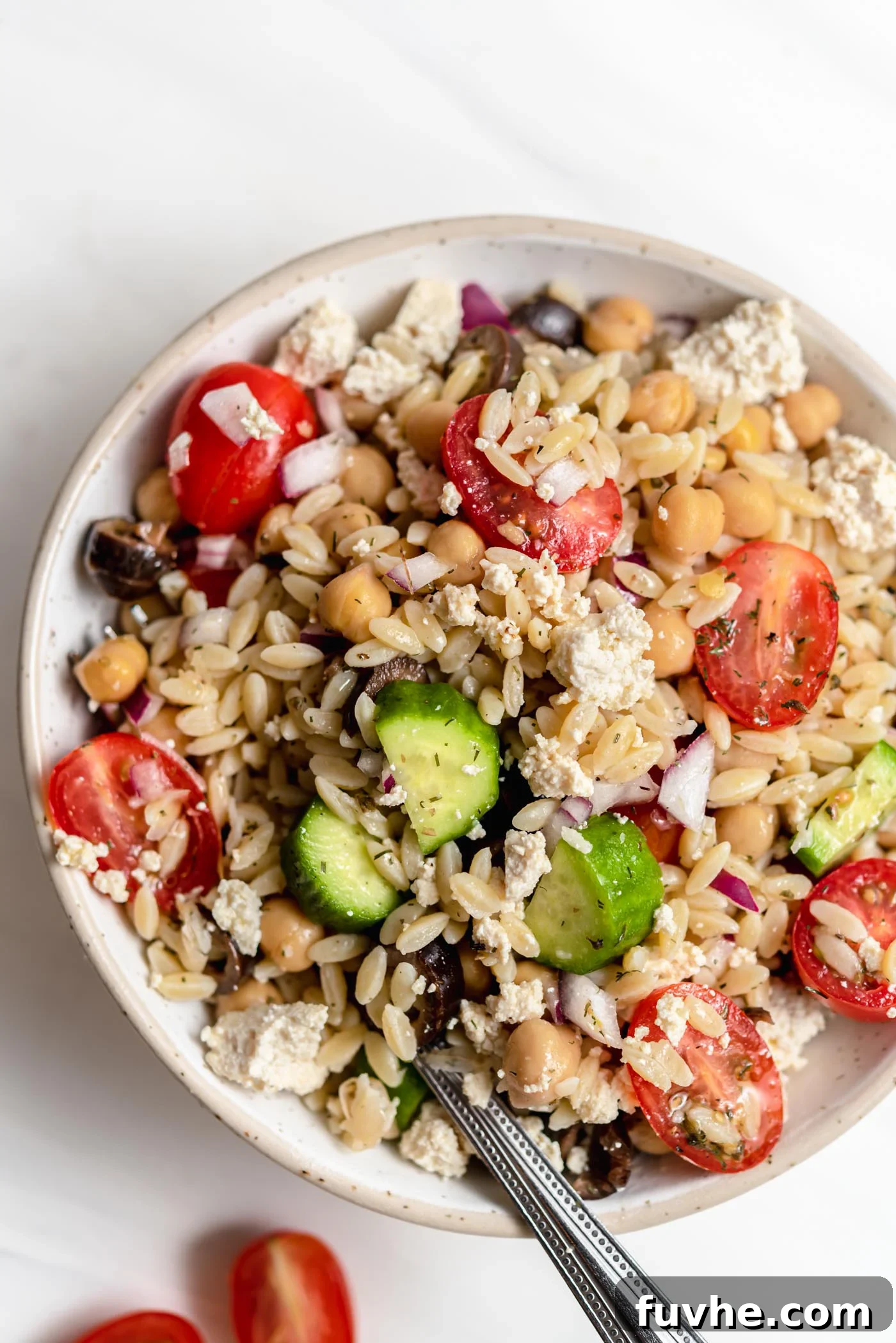 Overhead view of bowl of Mediterranean orzo salad with tomato, cucumber and olives.