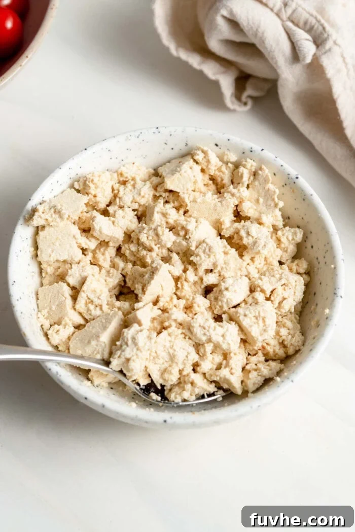 Crumbled tofu in a small bowl with a spoon.