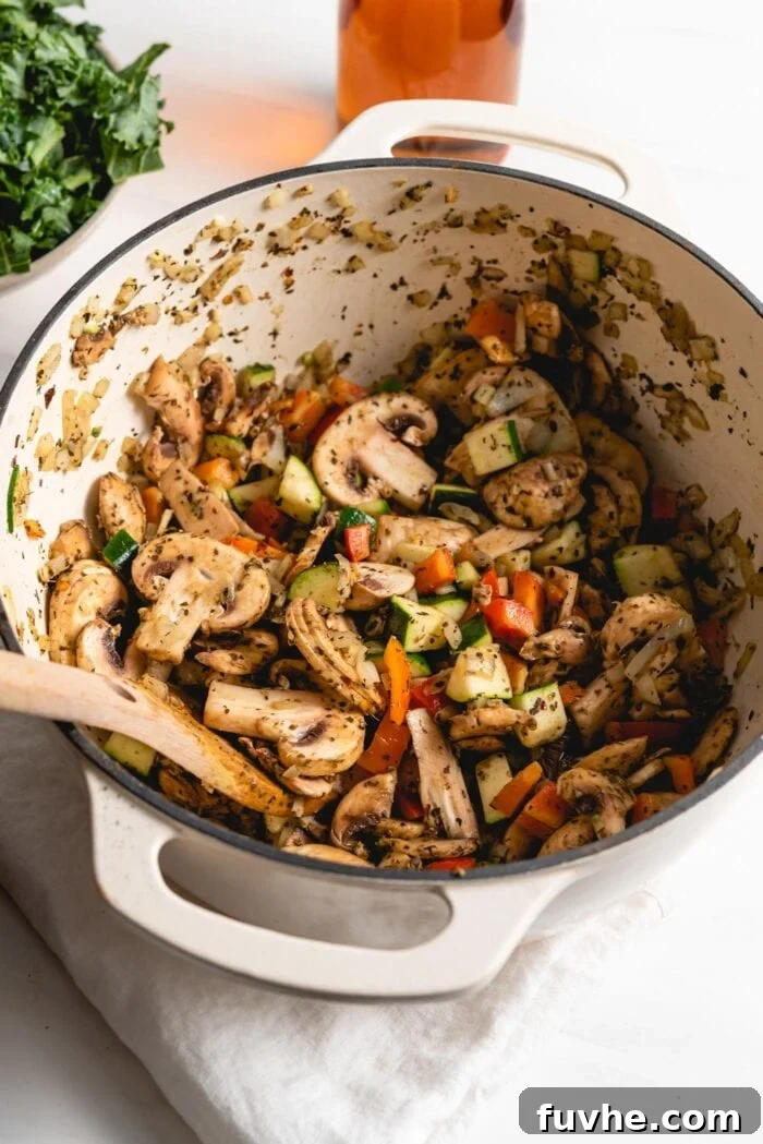 Diced zucchini, sliced mushrooms, and chopped bell peppers sautéing together in the large pot, softening and mingling their flavors.