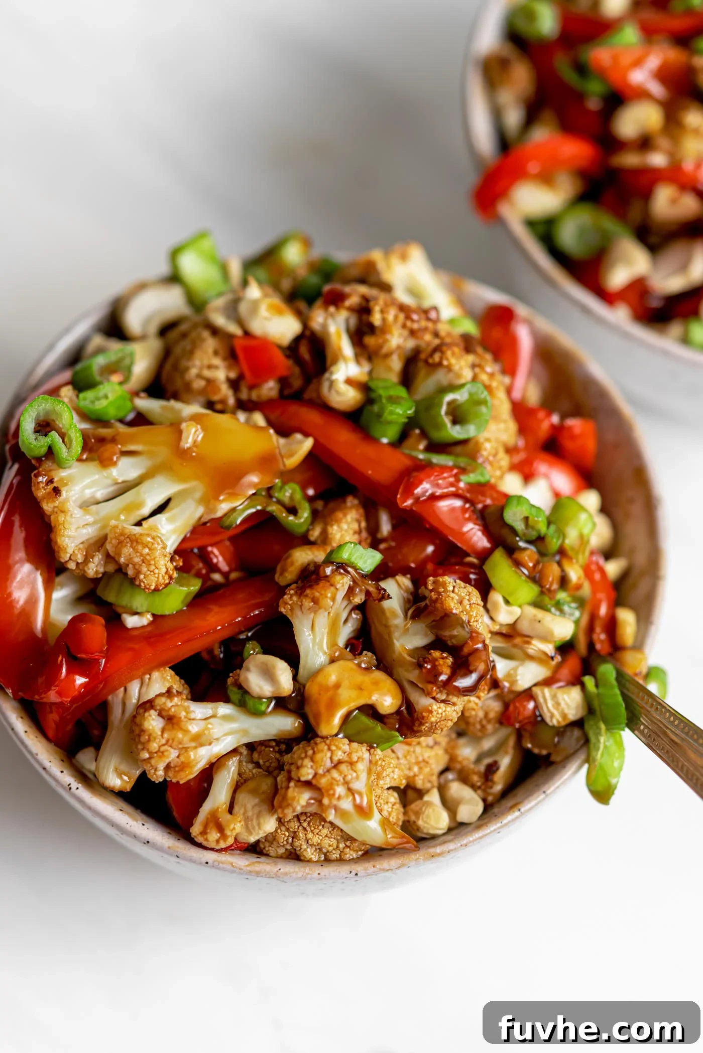 Crispy Kung Pao Cauliflower 2 Two bowls of cauliflower kung pao topped with chopped green onions and cashews.