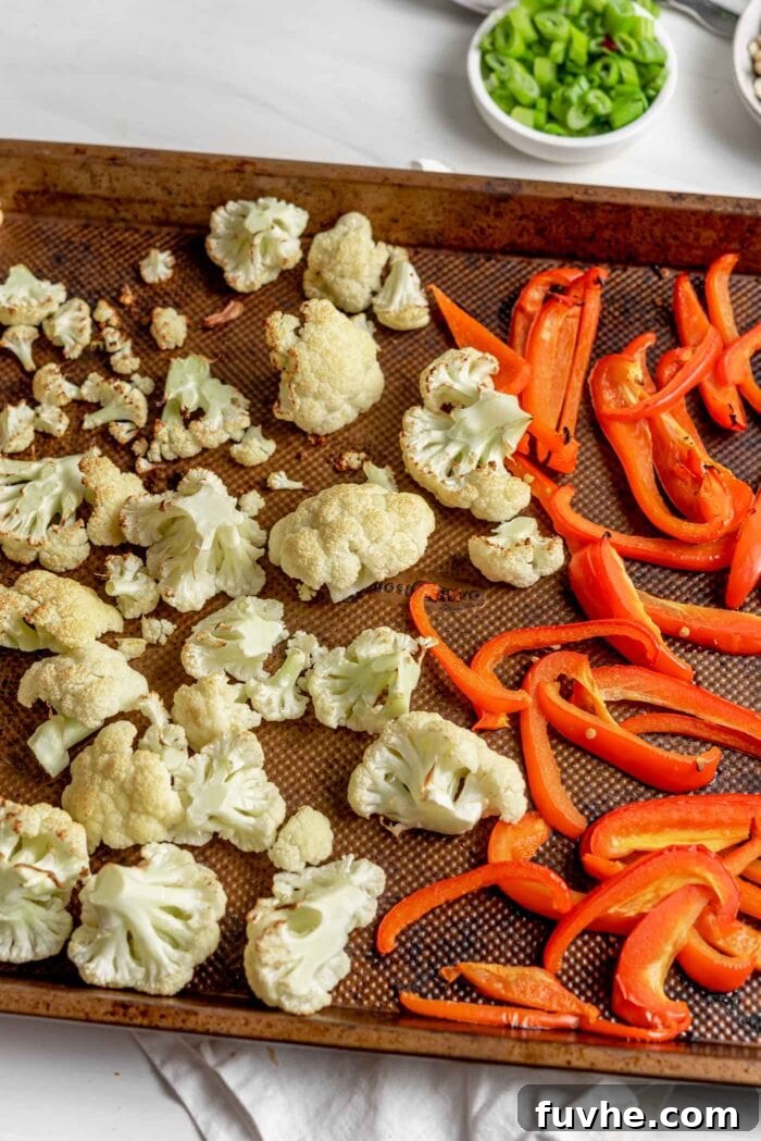Crispy Kung Pao Cauliflower 4 Roasted cauliflower and red bell peppers on a baking pan.