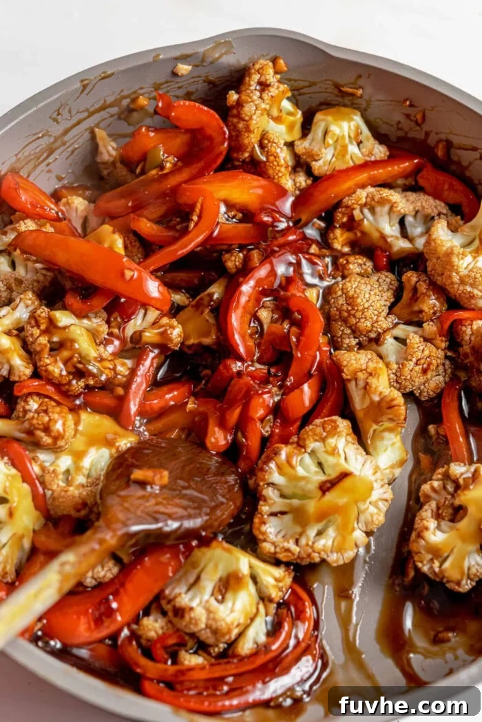 Crispy Kung Pao Cauliflower 6 Cauliflower and bell peppers mixed in a thick brown sauce in a pan.