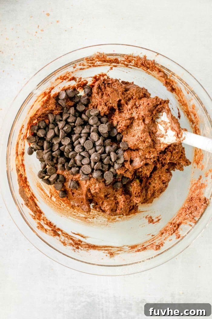Fudgy Plant-Based Chocolate Zucchini Loaf 8 Chocolate chips added to chocolate batter in a mixing bowl.
