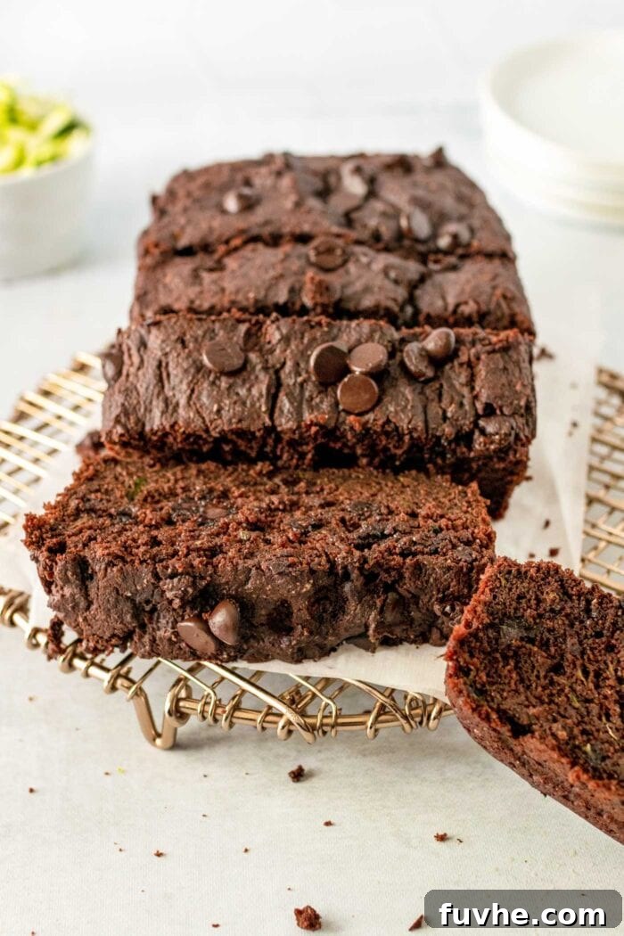 Fudgy Plant-Based Chocolate Zucchini Loaf 10 Sliced chocolate loaf with chocolate chips on a cooling rack.