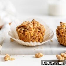 Small carrot muffin in a cupcake liner sitting on a marble cutting board, ready to be enjoyed as a healthy, delicious treat.