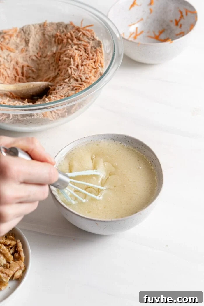 Whisking together unsweetened applesauce, melted coconut oil, vanilla extract, dairy-free milk, and apple cider vinegar in a small separate bowl to prepare the wet ingredients.