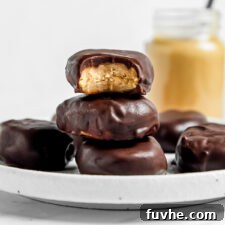 Stack of 3 peanut butter eggs on a plate, one on top with a bite out of it to show the texture inside.