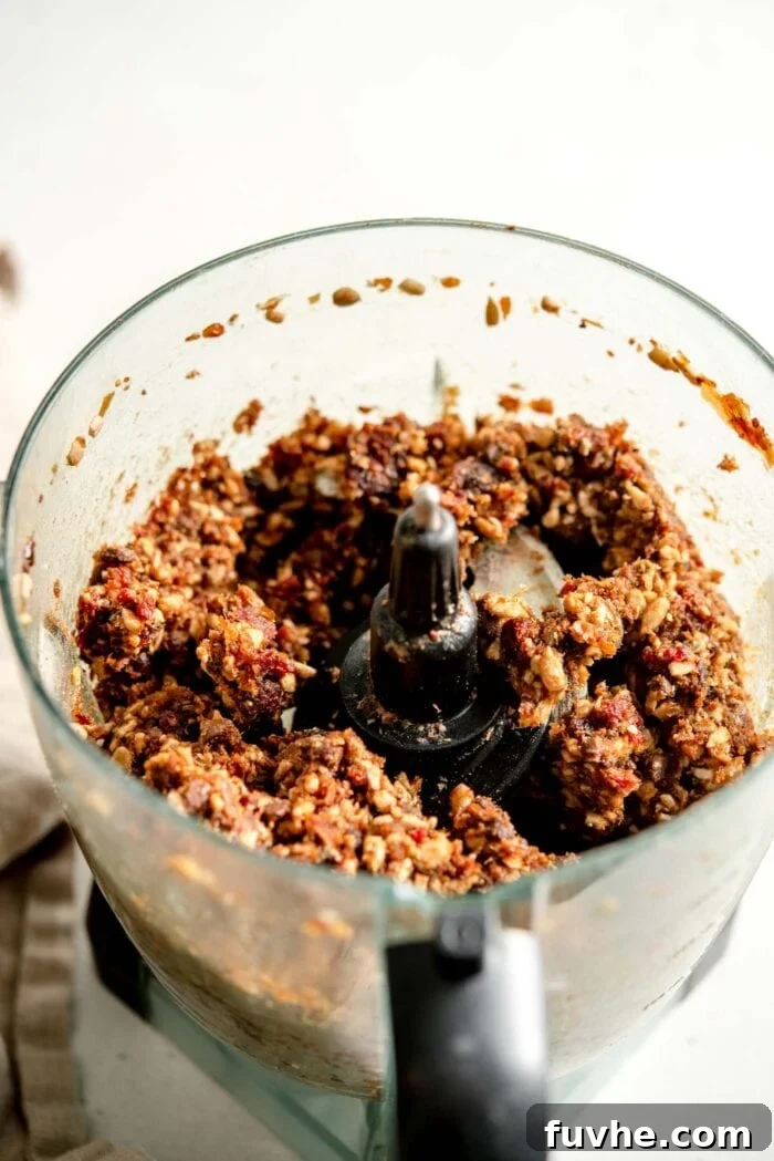 Thick, sticky dough made from dates and sunflower seeds in a food processor. The mixture is well-combined and ready for rolling.