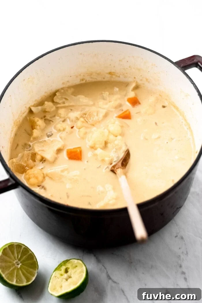 Cauliflower and sweet potato being mixed into soup in a stock pot.