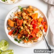 Overhead view of a bowl of sweet potato and chickpea curry topped with peanuts and over rice.