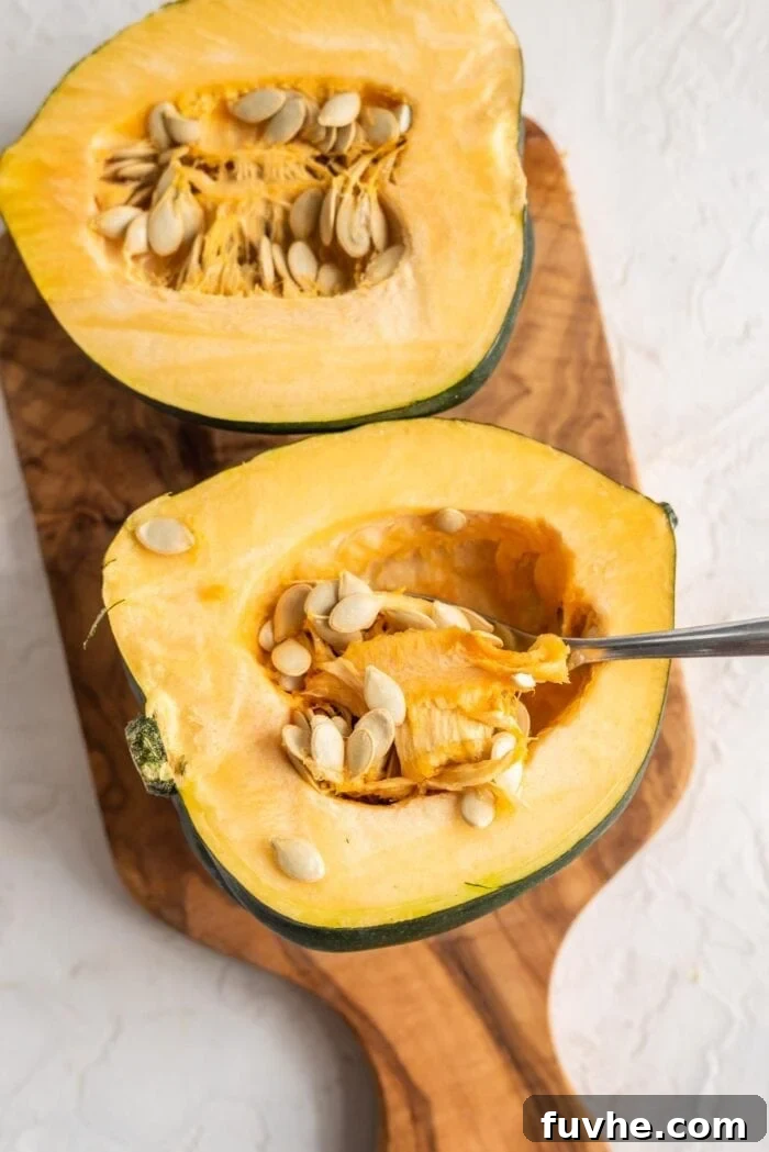Golden Acorn Feast 3 Two acorn squash halves with the spoon scooping out the seeds, showing the preparation process.