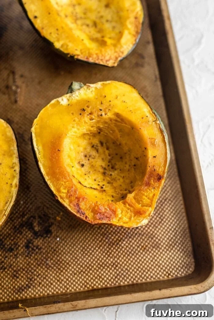 Golden Acorn Feast 5 Half of a roasted acorn squash sprinkled with salt and pepper on a baking tray, perfectly cooked.