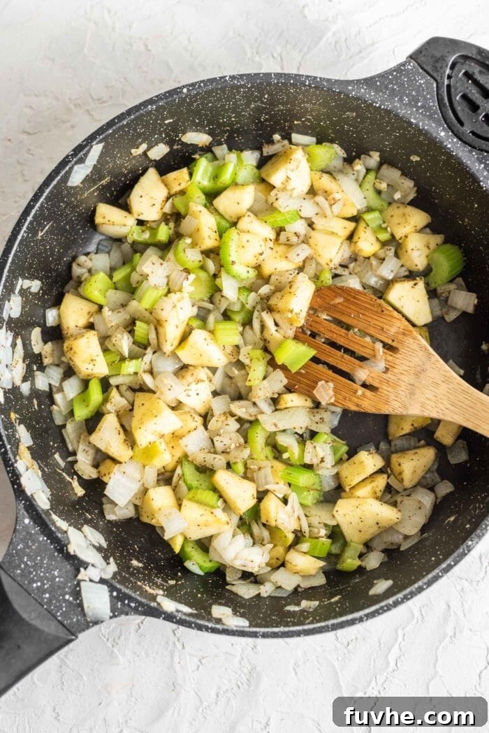 Golden Acorn Feast 7 Apple, celery, onion and garlic in a skillet with herbs, showing the added ingredients.