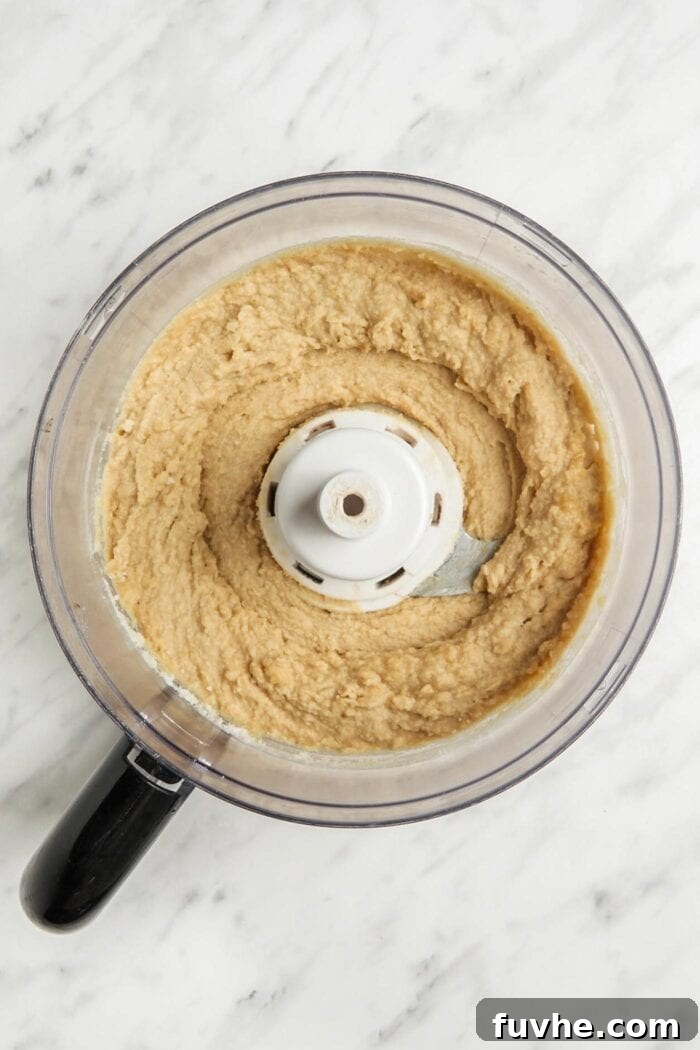 Blended chickpea brownie batter in a food processsor, smooth and ready for chocolate chips.