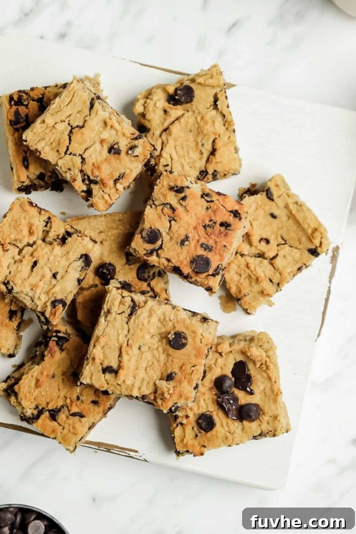 Numerous sliced chocolate chip blondies on a wooden cutting board, showcasing their ready-to-eat perfection.