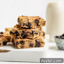 Stack of 3 chocolate chip blondies on a cutting board.