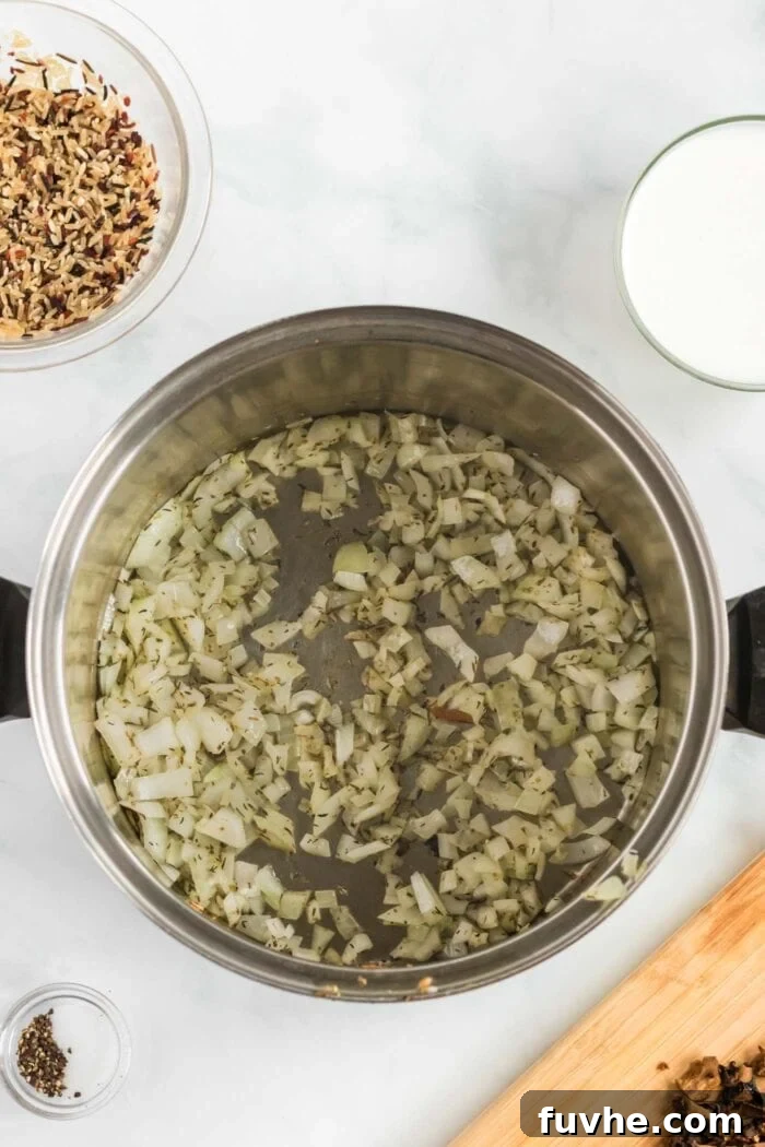 Diced onions gently sautéing in a soup pot with aromatic herbs like thyme and oregano, releasing their sweet fragrances.