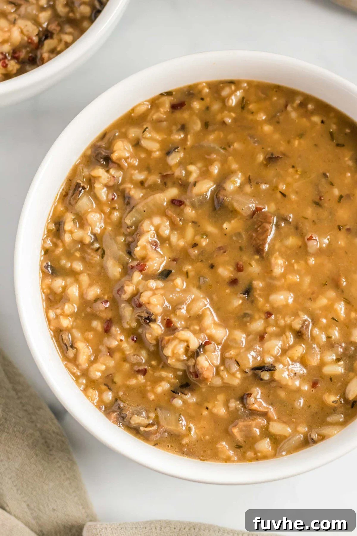 A close-up shot of a single serving bowl of creamy wild rice mushroom soup, garnished and ready to be enjoyed.