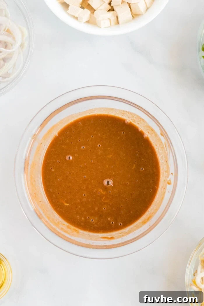 A small glass bowl filled with the rich, homemade Pad Thai sauce, showcasing its smooth texture and appetizing color, ready to be incorporated into the dish.