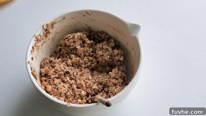 Superfood Quinoa Energy Bars 6 A thick mixture of oats, quinoa and mashed banana in a mixing bowl with a spoon in it.