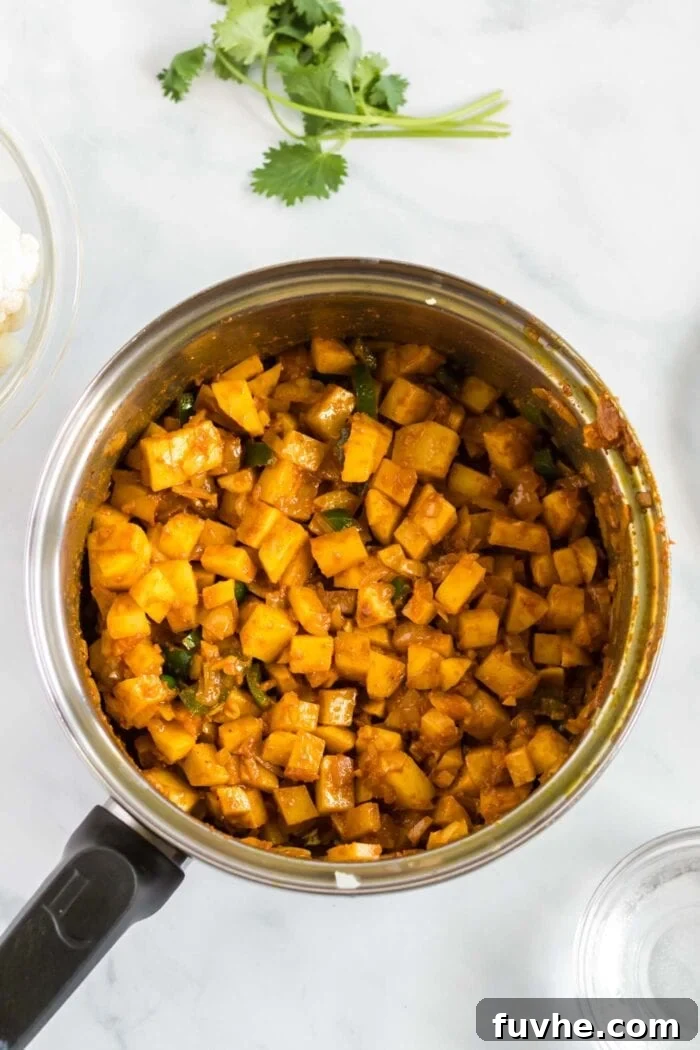 Comforting Cauliflower Potato Curry 6 Diced Yukon gold potatoes are added to the pot, simmering gently in the rich, spiced curry paste, absorbing all the aromatic flavors.