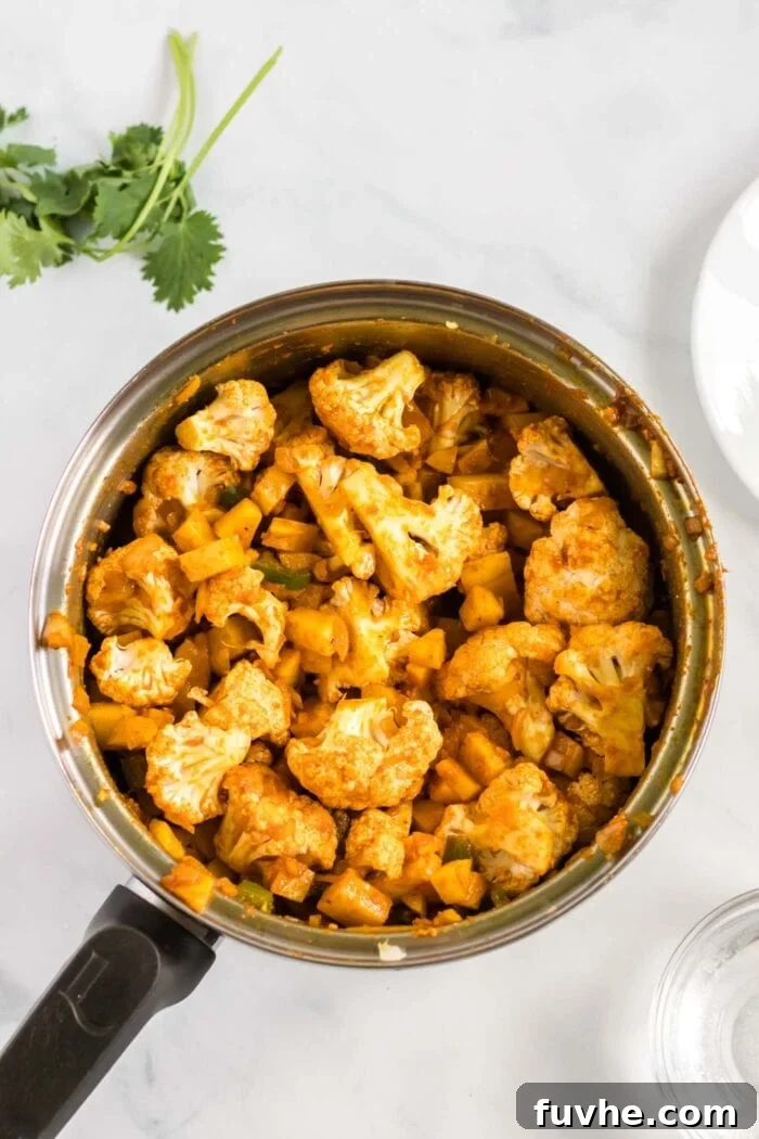 Comforting Cauliflower Potato Curry 7 The chopped cauliflower florets are now combined with the spiced potatoes in the pot, ready to be cooked until tender in the aromatic curry sauce.