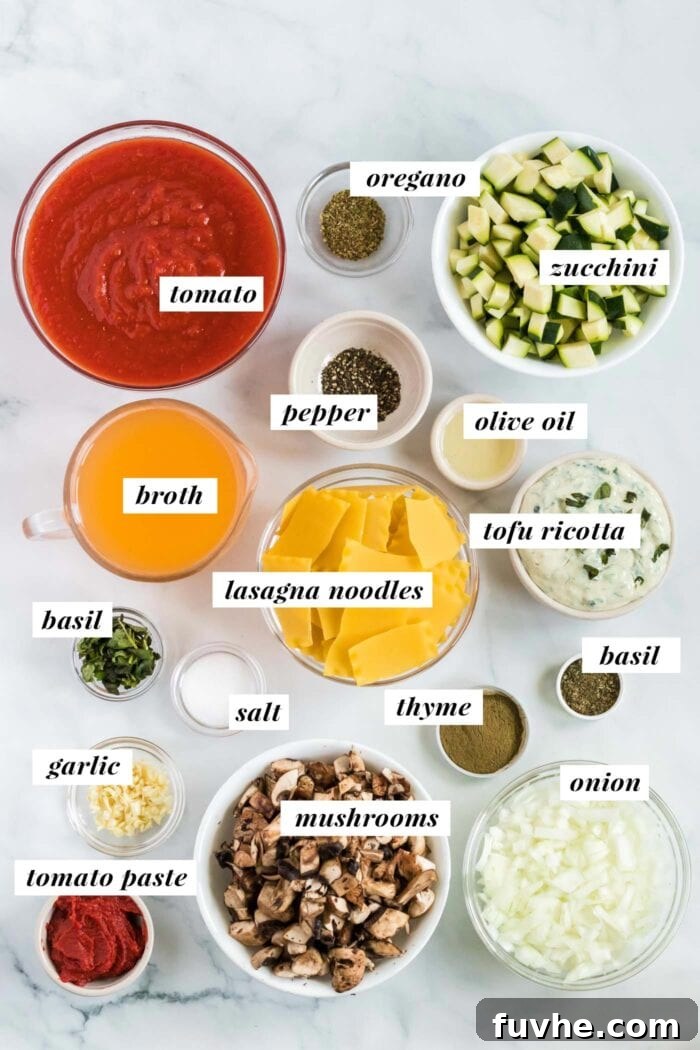 A visual spread of fresh vegetables including onions, garlic, mushrooms, zucchini, along with canned tomatoes, herbs, and pasta, laid out for making vegan lasagna soup.