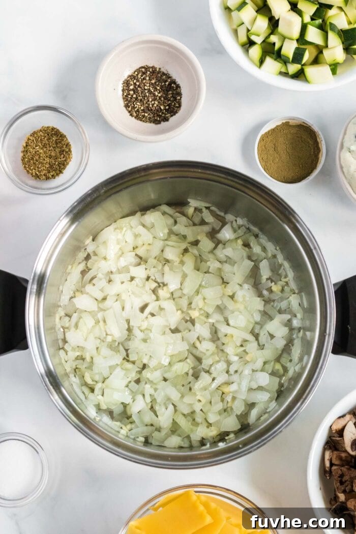 Diced onion and minced garlic gently sizzling in olive oil within a large soup pot, forming the aromatic base of the soup.