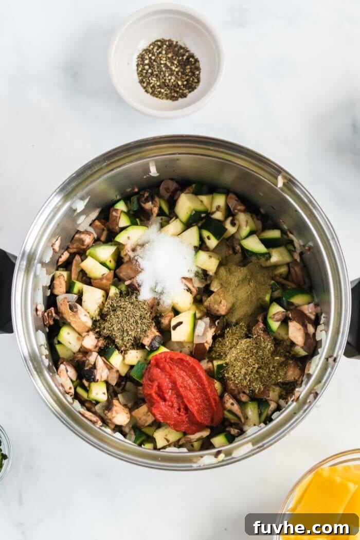 Tomato paste, dried herbs, and salt being stirred into the softened vegetables in the soup pot, intensifying the flavors.