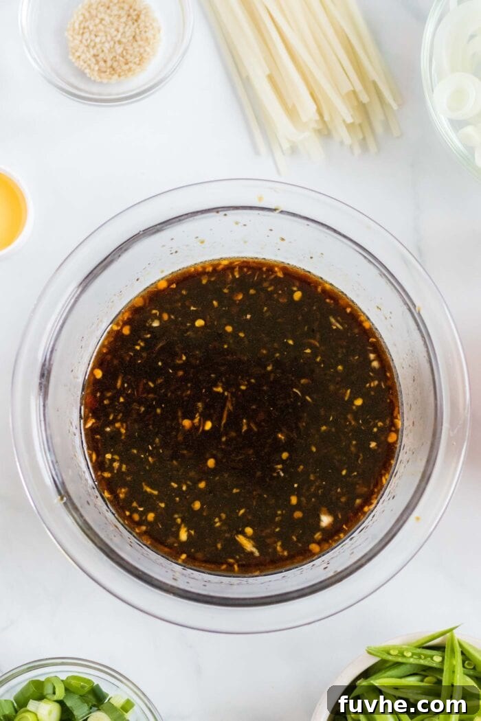 Lo mein sauce whisked together in a small glass bowl, ready to be added to the stir-fry.