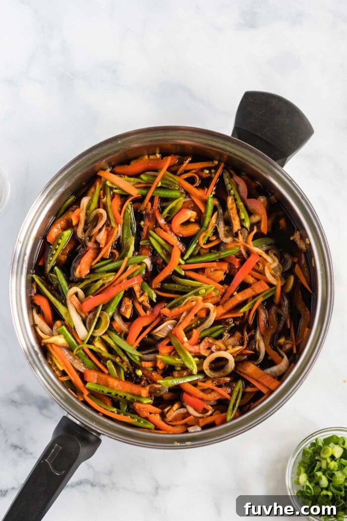 Stir-fried vegetables immersed in the rich lo mein sauce, simmering gently.