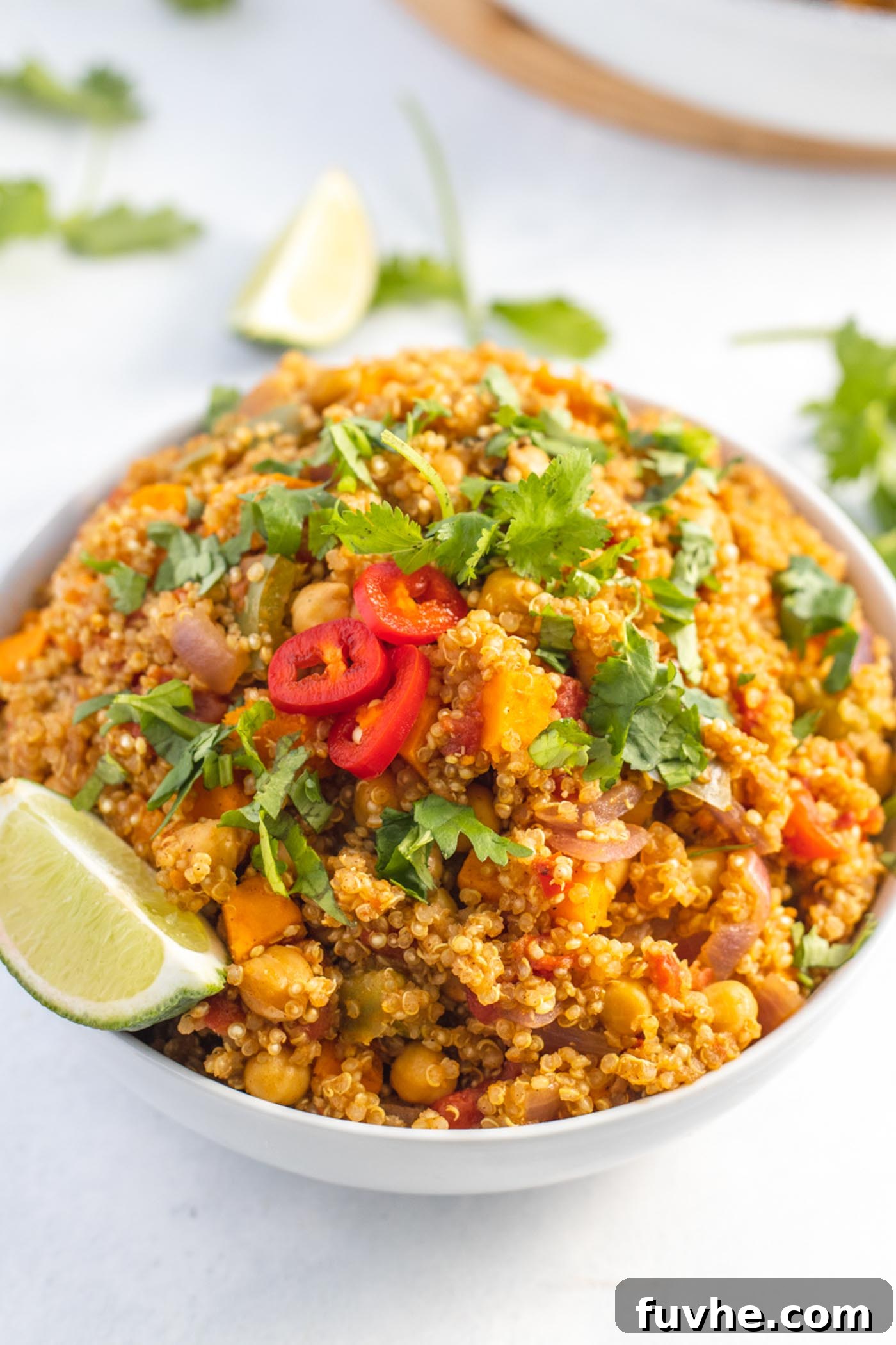 Hearty Sweet Potato Quinoa Skillet 2 Large bowl of curried quinoa with chickpeas and sweet potato topped with sliced chilis and cilantro.