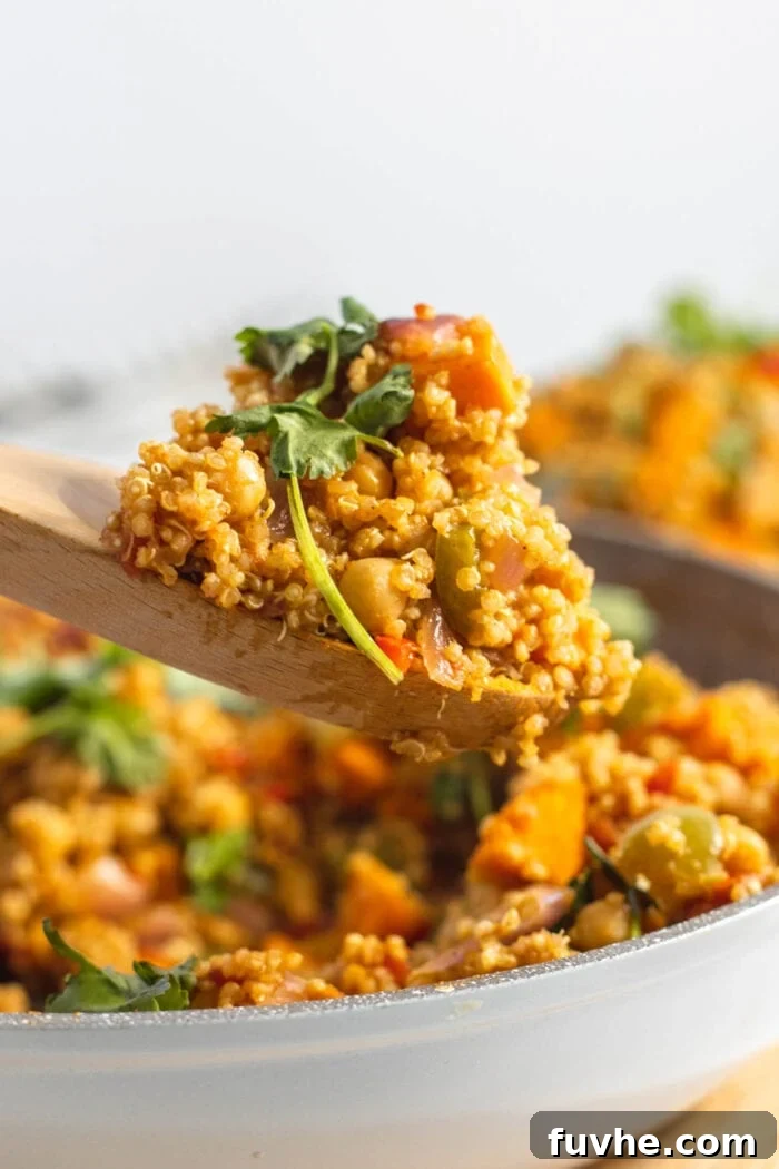 Hearty Sweet Potato Quinoa Skillet 8 Wooden spoon with a spoonful of curried quinoa on it.