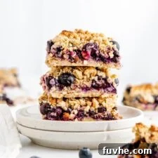 Stack of 3 vegan gluten-free blueberry crumble bars on a small plate.