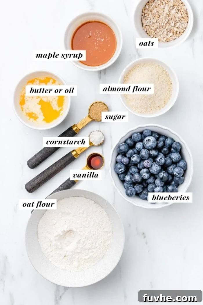 A selection of fresh ingredients, including blueberries, flours, and syrup, neatly arranged for making vegan blueberry crumble bars.