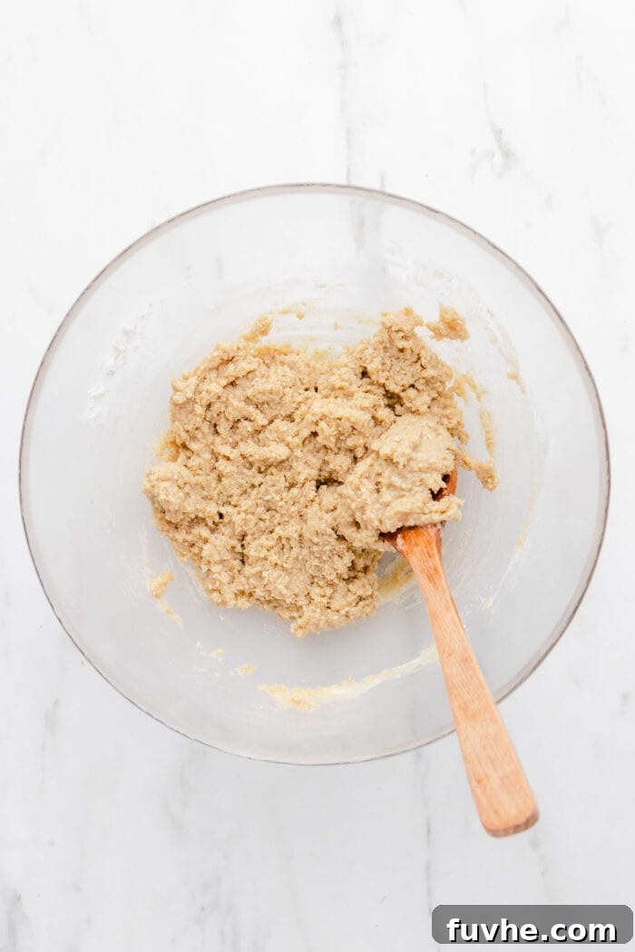 Plant-Based Key Lime Paradise 4 Raw pie crust batter made from oats and almonds, gently resting in a mixing bowl with a wooden spoon, ready to be pressed into a tart pan.