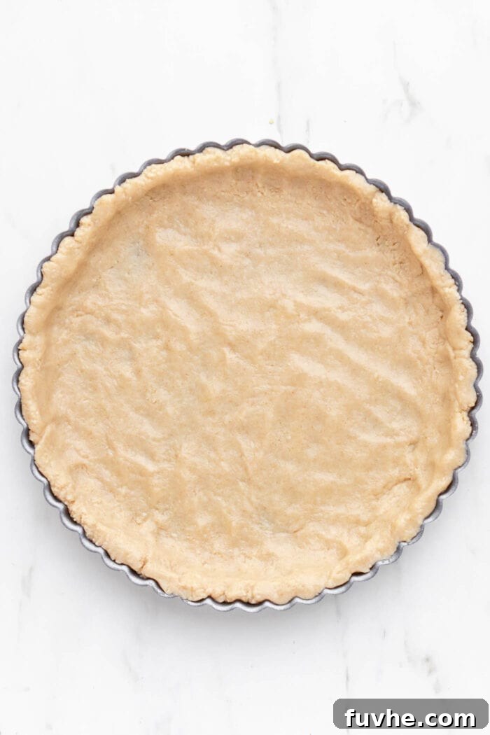 Plant-Based Key Lime Paradise 5 An unbaked pie crust, perfectly pressed and shaped into a tart pan, awaiting its creamy filling.