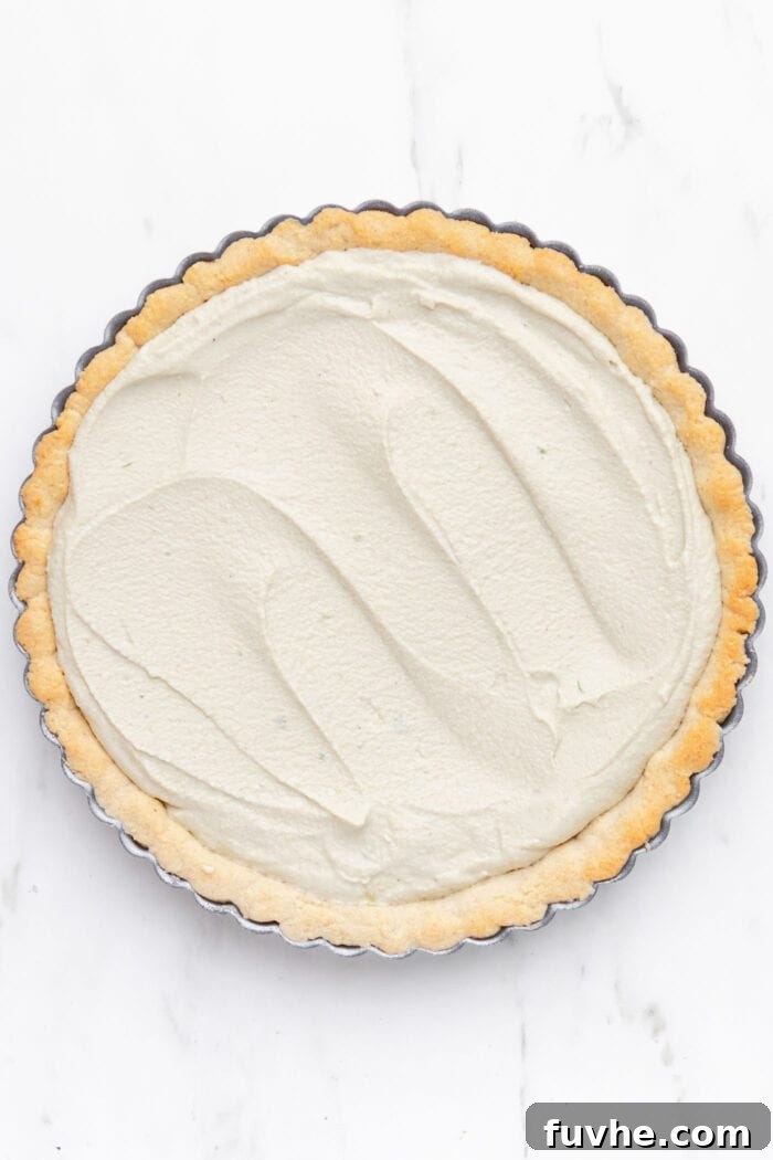 Plant-Based Key Lime Paradise 6 An overhead view of a raw vegan key lime pie, newly assembled with its creamy green filling in the crust, prior to chilling and setting.
