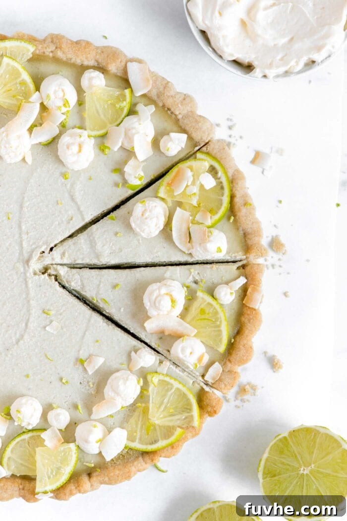 Plant-Based Key Lime Paradise 7 Overhead view of a beautifully presented vegan key lime pie, garnished with fresh lime wedges and dollops of rich coconut whipped cream, making it a truly inviting dessert.