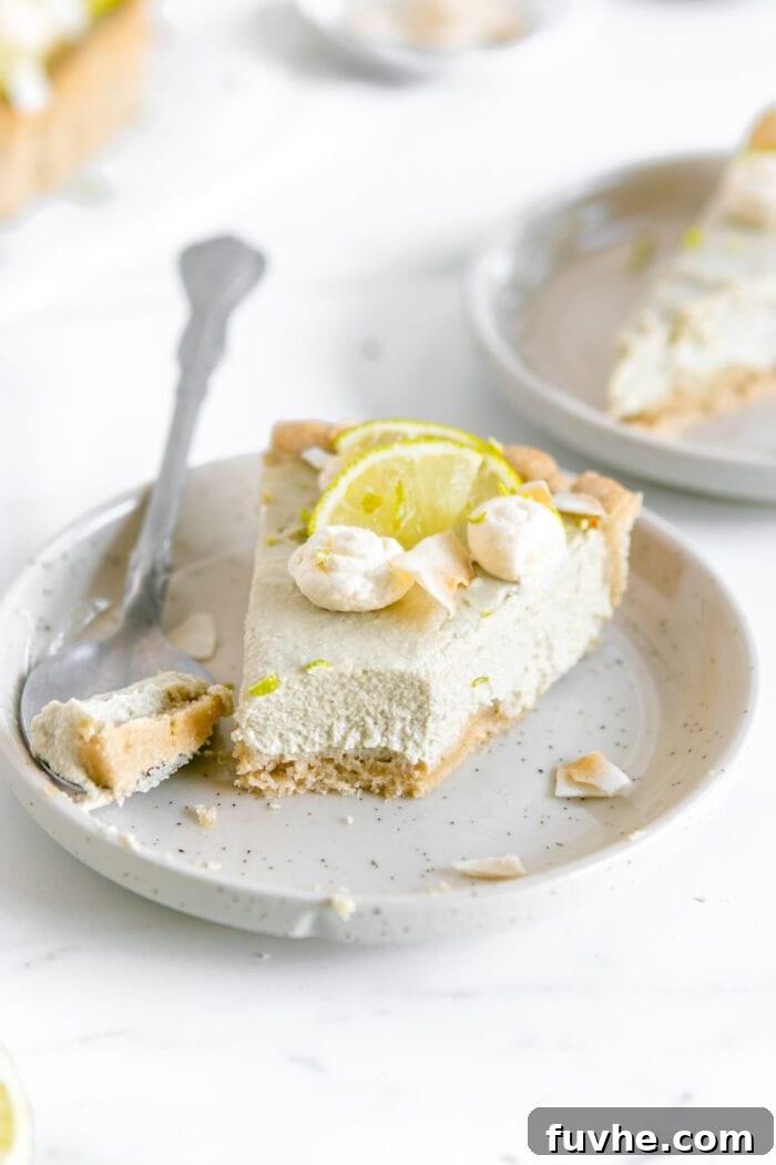 Plant-Based Key Lime Paradise 8 A perfectly portioned slice of vegan key lime pie on a white plate, with a small bite taken out and a fork resting beside it, highlighting its creamy texture.