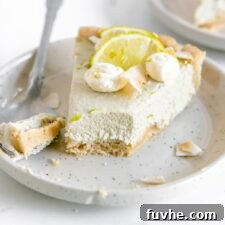 A delectable slice of vegan key lime pie on a plate, garnished with lime and whipped cream, inviting you to take a bite.