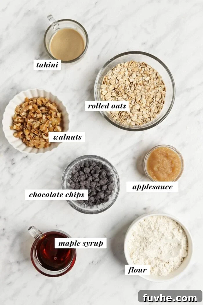 Visual list of ingredients for making tahini oatmeal breakfast cookies, including oats, flour, walnuts, maple syrup, tahini, applesauce, and chocolate chips.